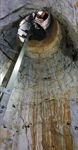 looking up to t eh entrance to chalk mines,  a circular hole reached by a metal ladder